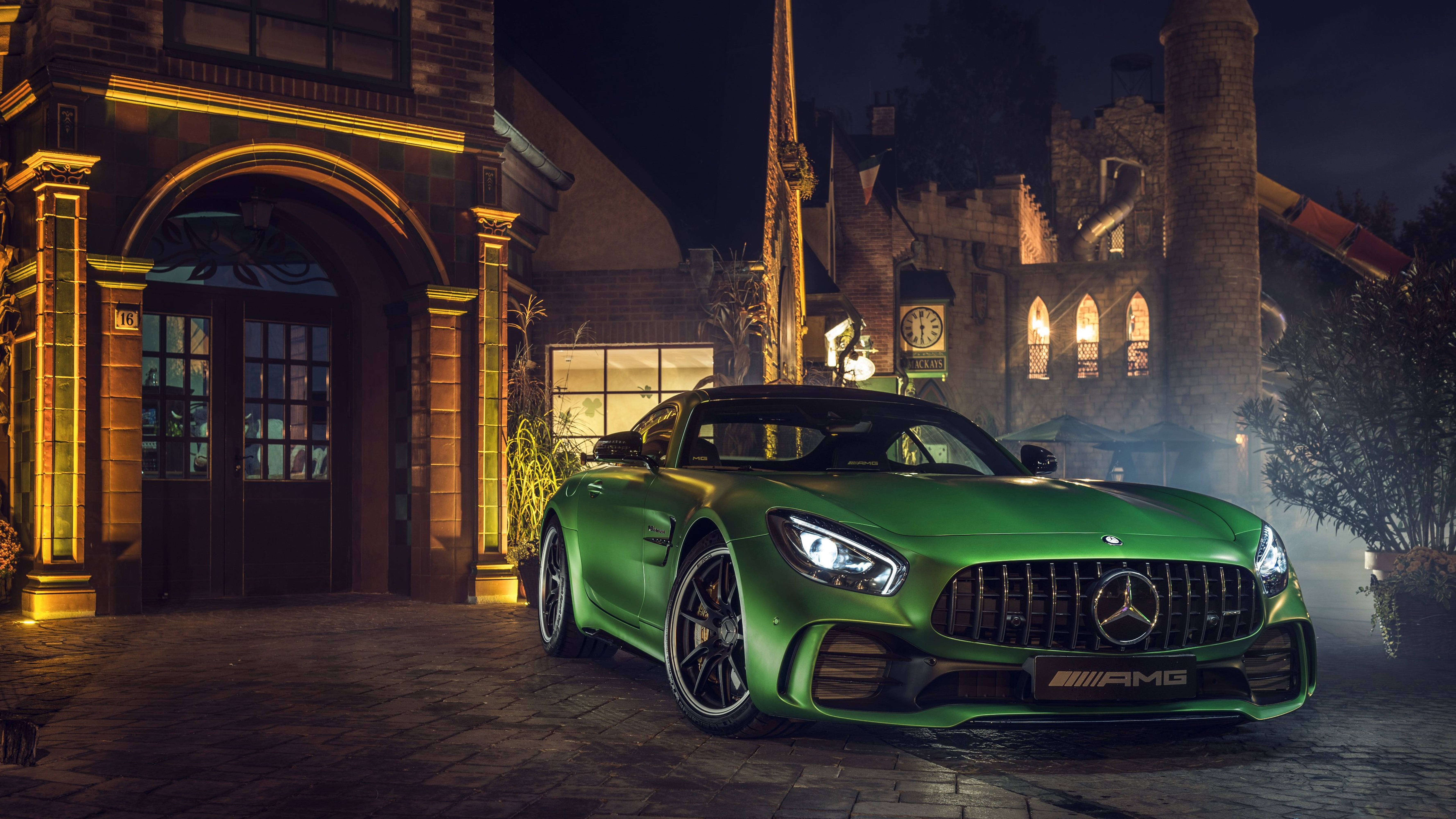 Caption: Striking Elegance - A Mercedes-amg In A Captivating Green Hue Standing Outside A Modernistic Building. Background