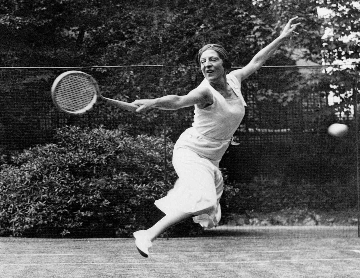 Caption: Suzanne Lenglen In Action With A Classic Backhand Stance Background
