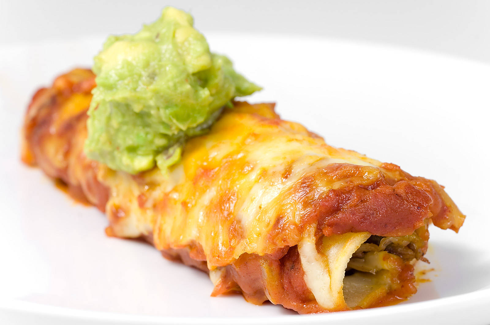 Caption: Tasty Enchilada Rolls Topped With Fresh Guacamole Background