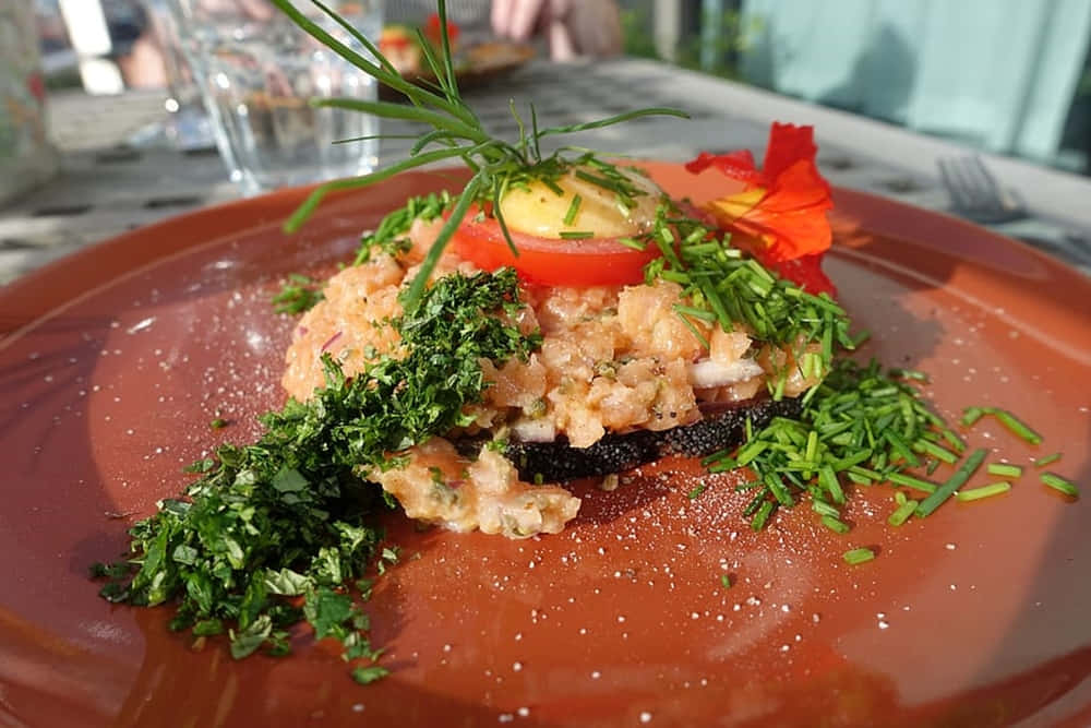 Caption: Tasty Ground Salmon Dish Garnished With Chives On An Orange Plate Background