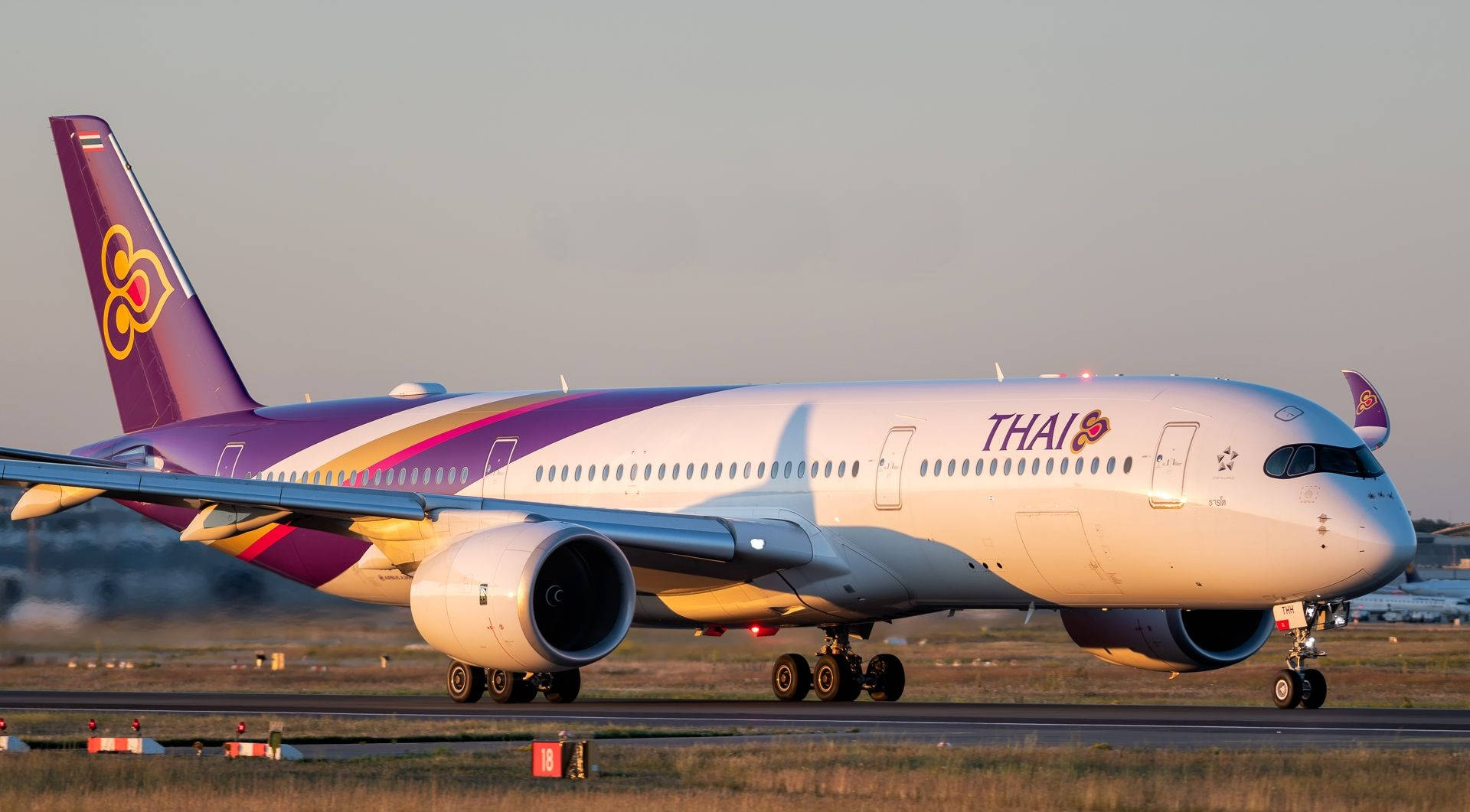 Caption: Thai Airways Airliner Landing On Runway Background