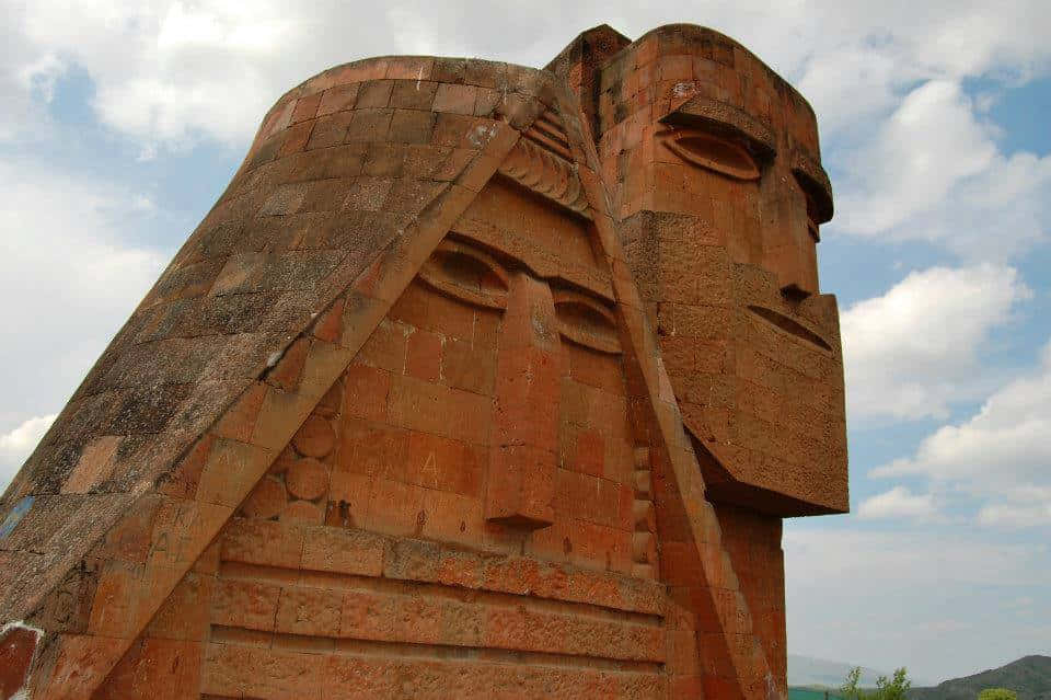 Caption: The Majestic We Are Our Mountains Monument Standing Tall Against A Cloudy Sky.