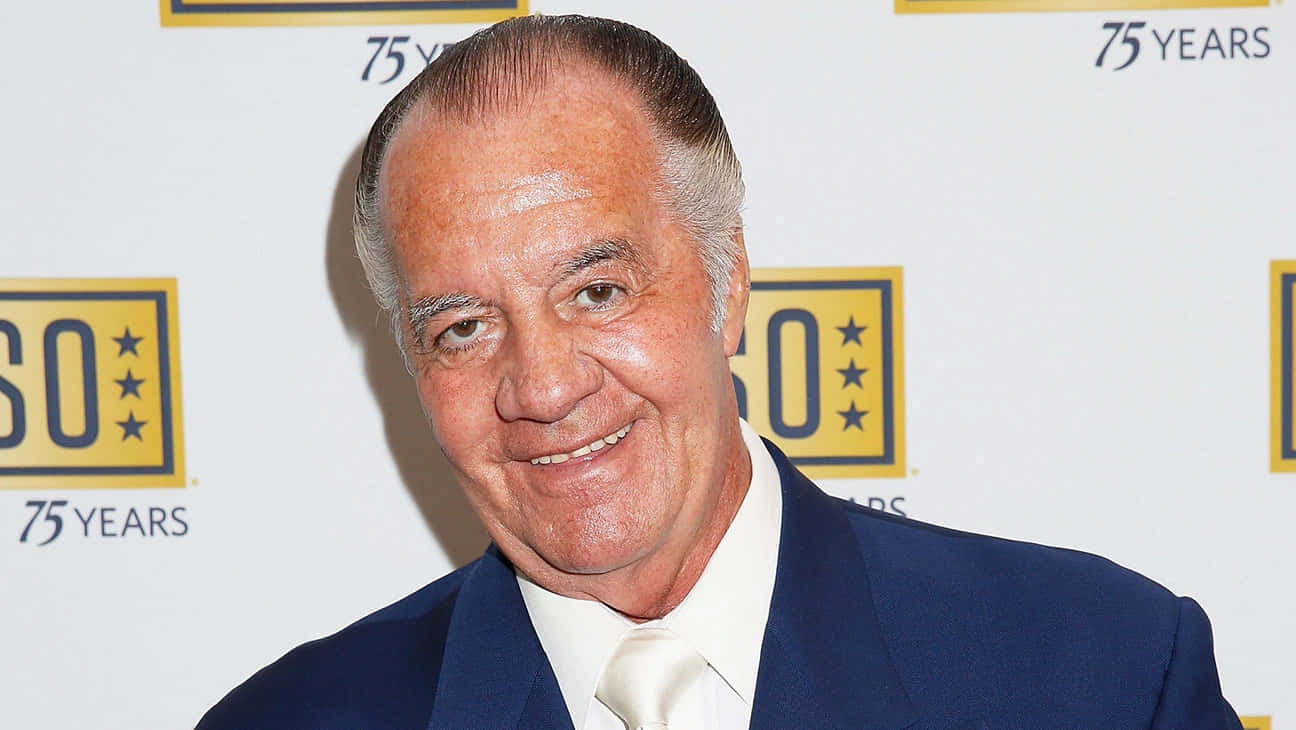Caption: Tony Sirico Striking A Pose In A Suit Background