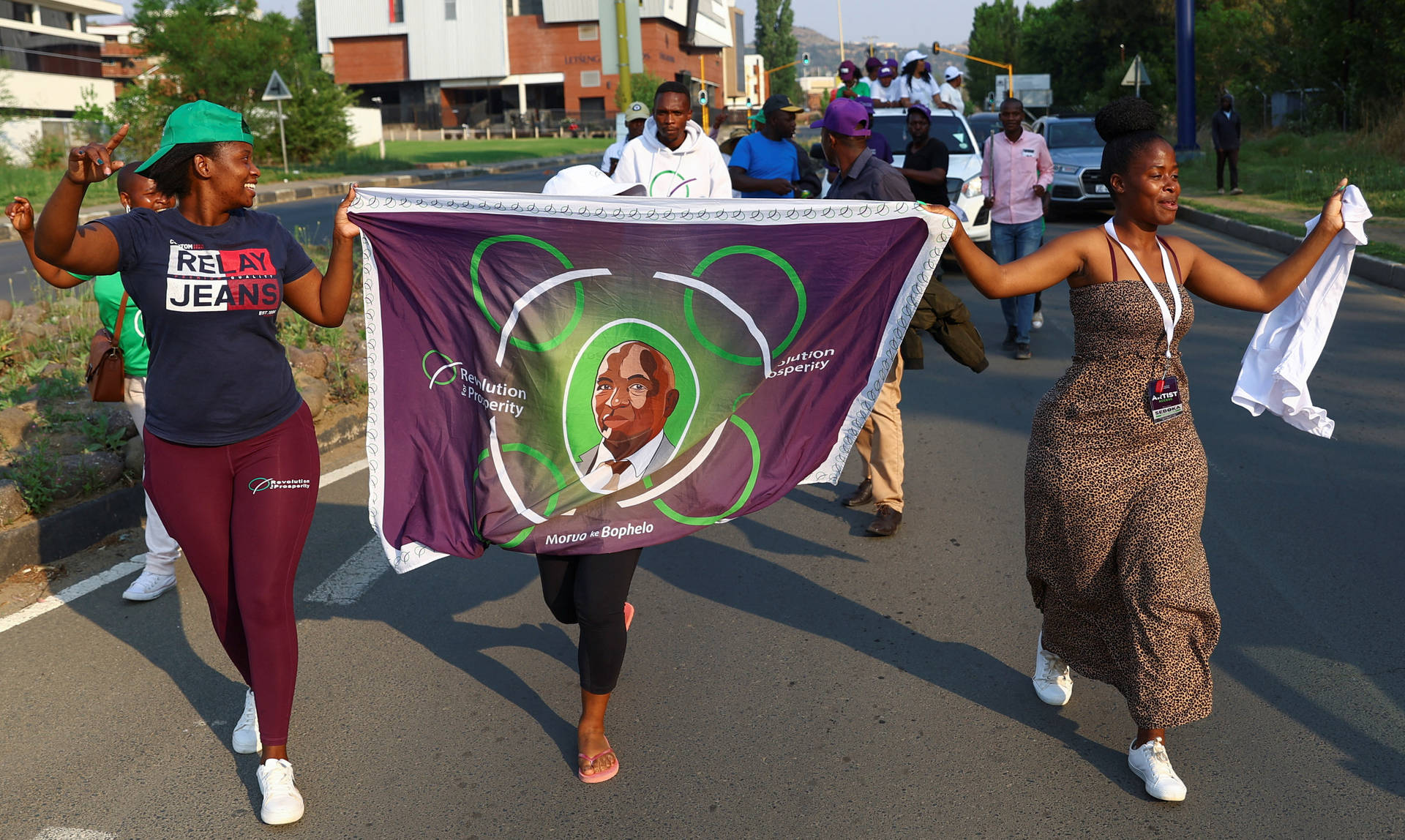 Caption: Vibrant Culture Of Lesotho - Women In Traditional Dress With King Letsie Iii Banner Background