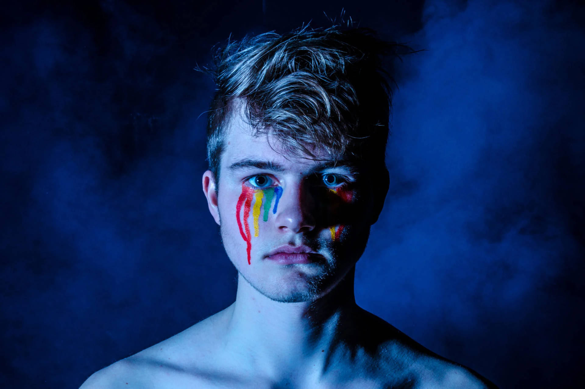 Caption: Young Man Showcasing Pride Makeup Background