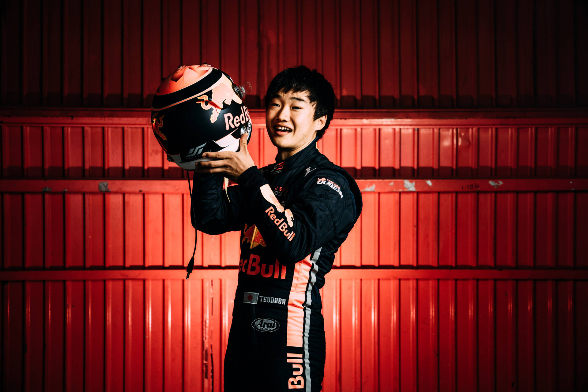 Caption: Yuki Tsunoda, With A Bright Smile, Holding His Helmet.