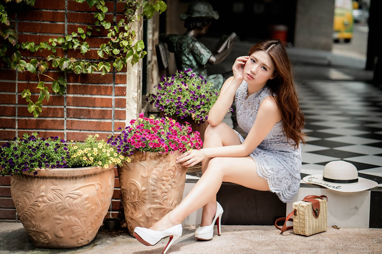 Captivating Asian Woman Posing Near Floral Display Background