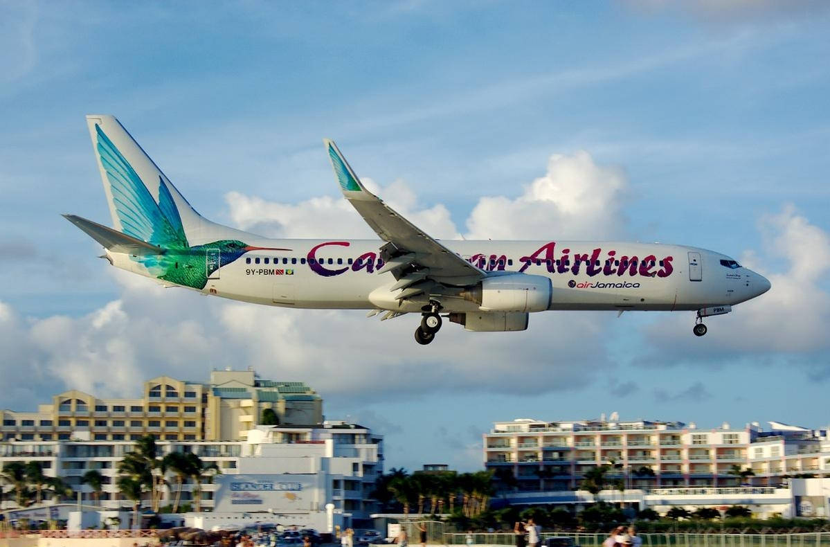 Caribbean Airlines Flying Above City Background