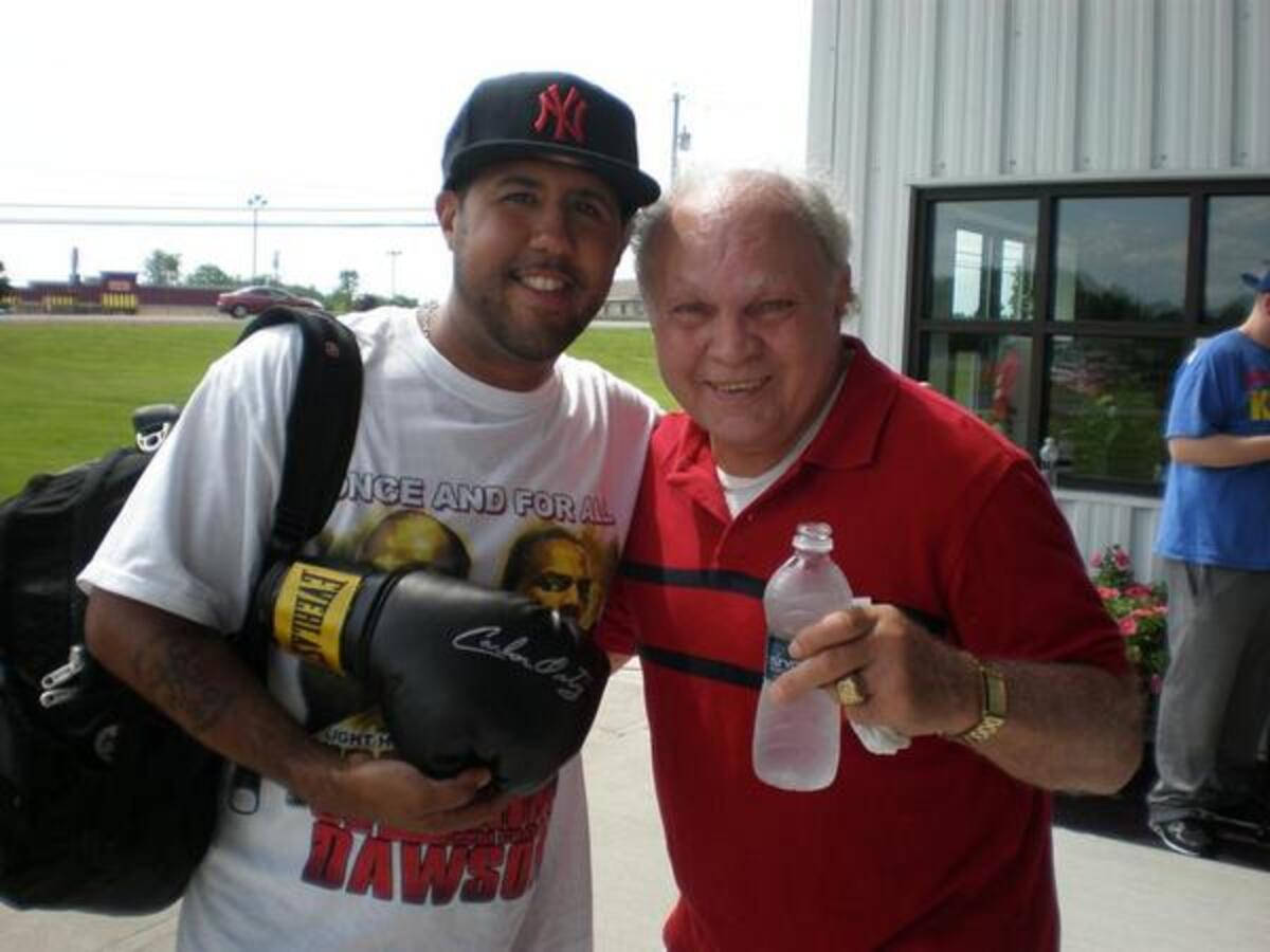 Carlos Ortiz Next To Fan With Boxing Glove Background