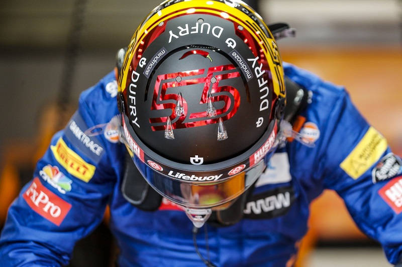 Carlos Sainz Jr., A Racehorse Running Through The Circuit In His Racing Gear. Background