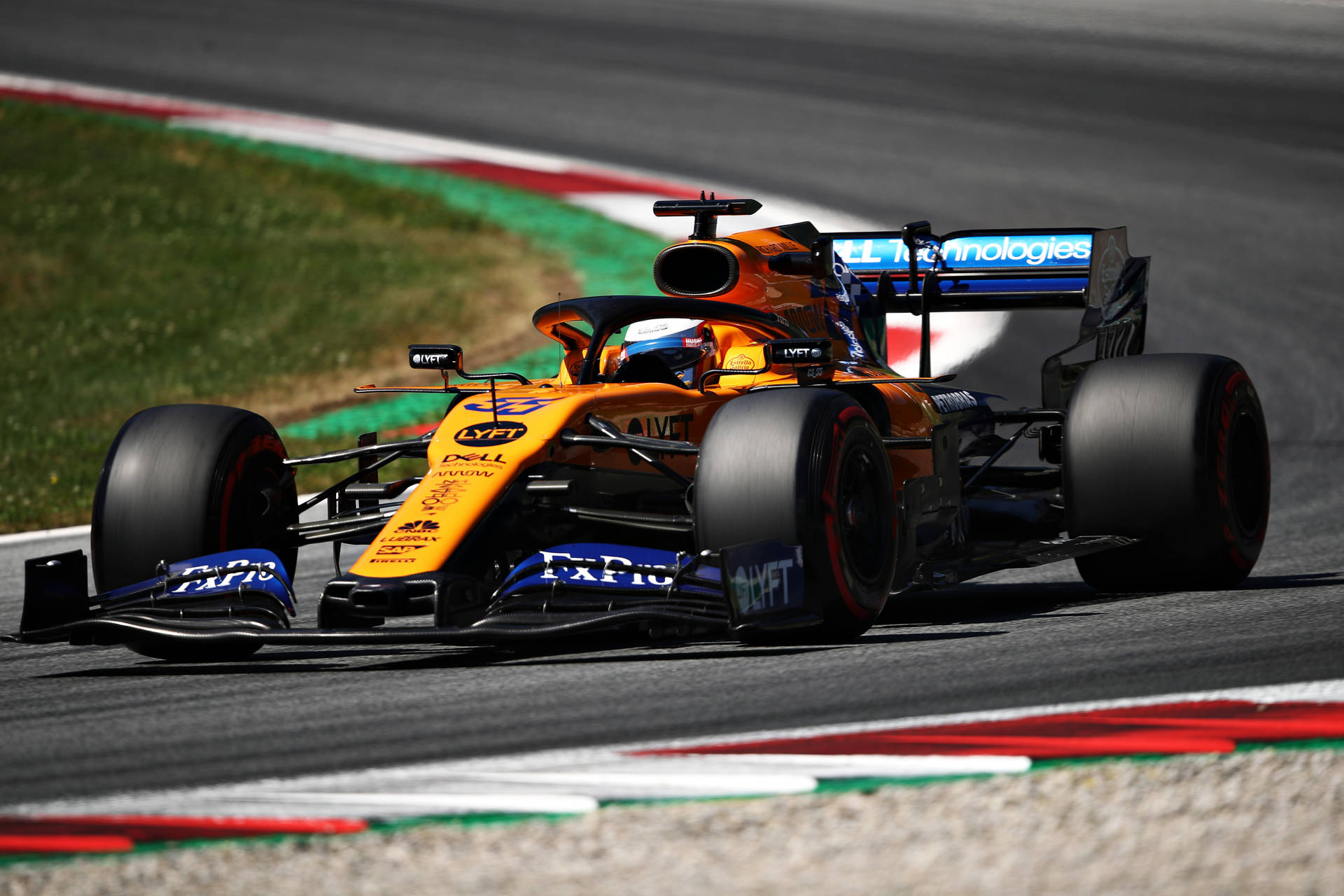 Carlos Sainz Jr. Speeding On The Track In His Yellow F1 Race Car Background