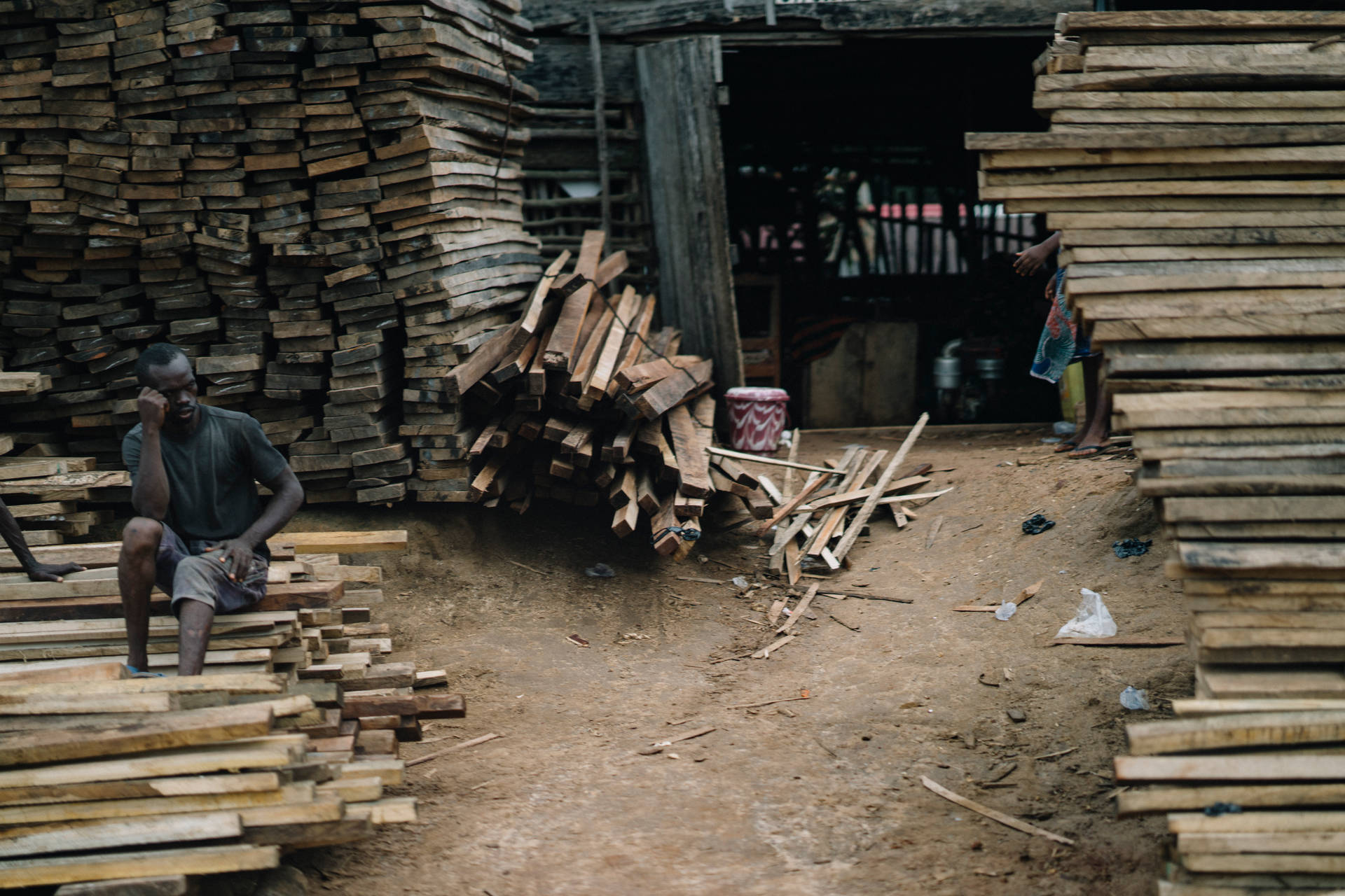 Carpenter With Stacks Of Wood In Sierra Leone Background