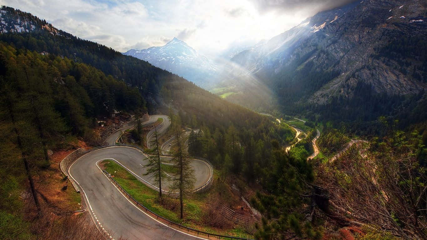 Cars Passing By A Winding Mountain Road Background