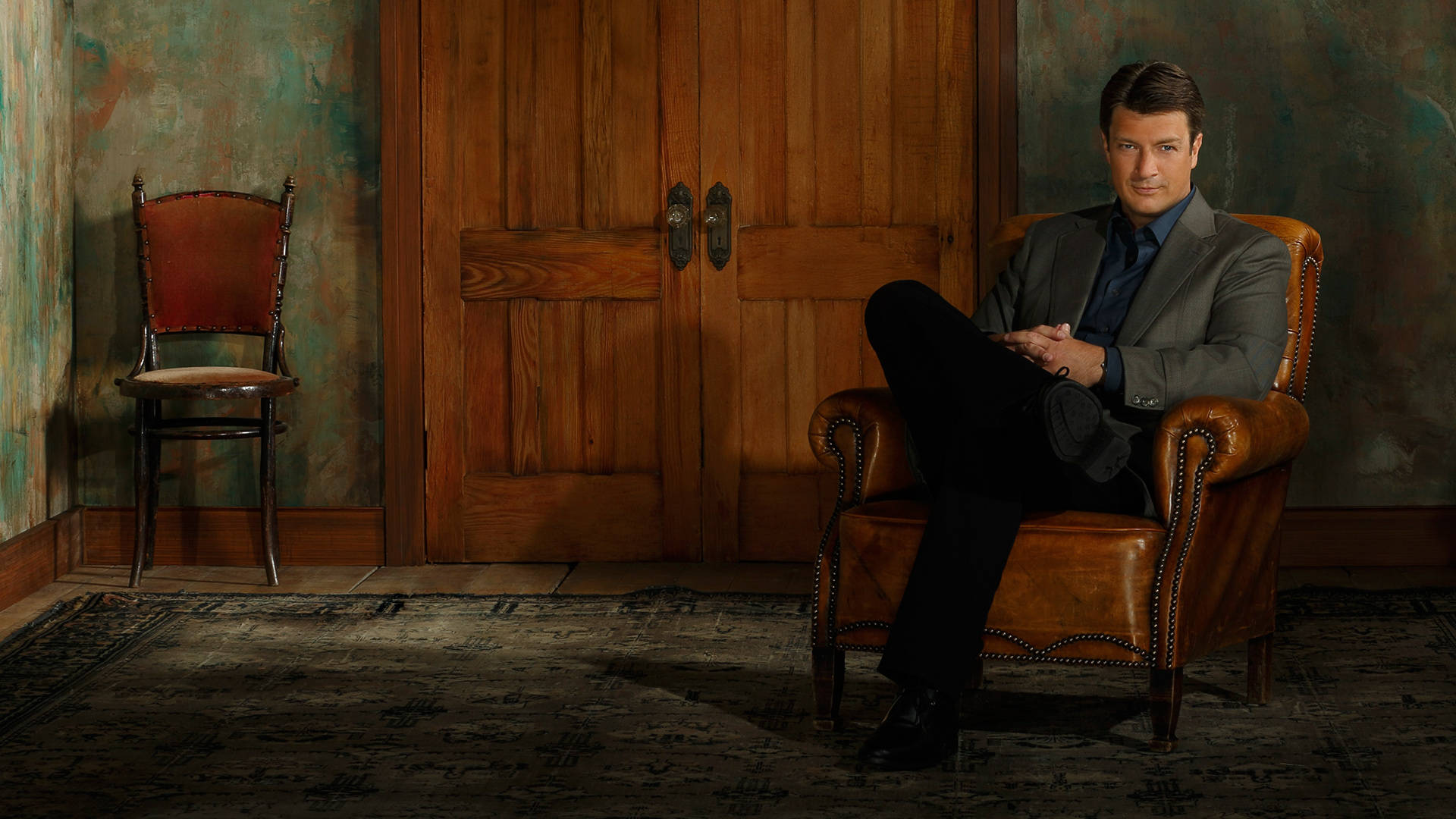 Casual Pose Of Actor Nathan Fillion Lounging On A Chair