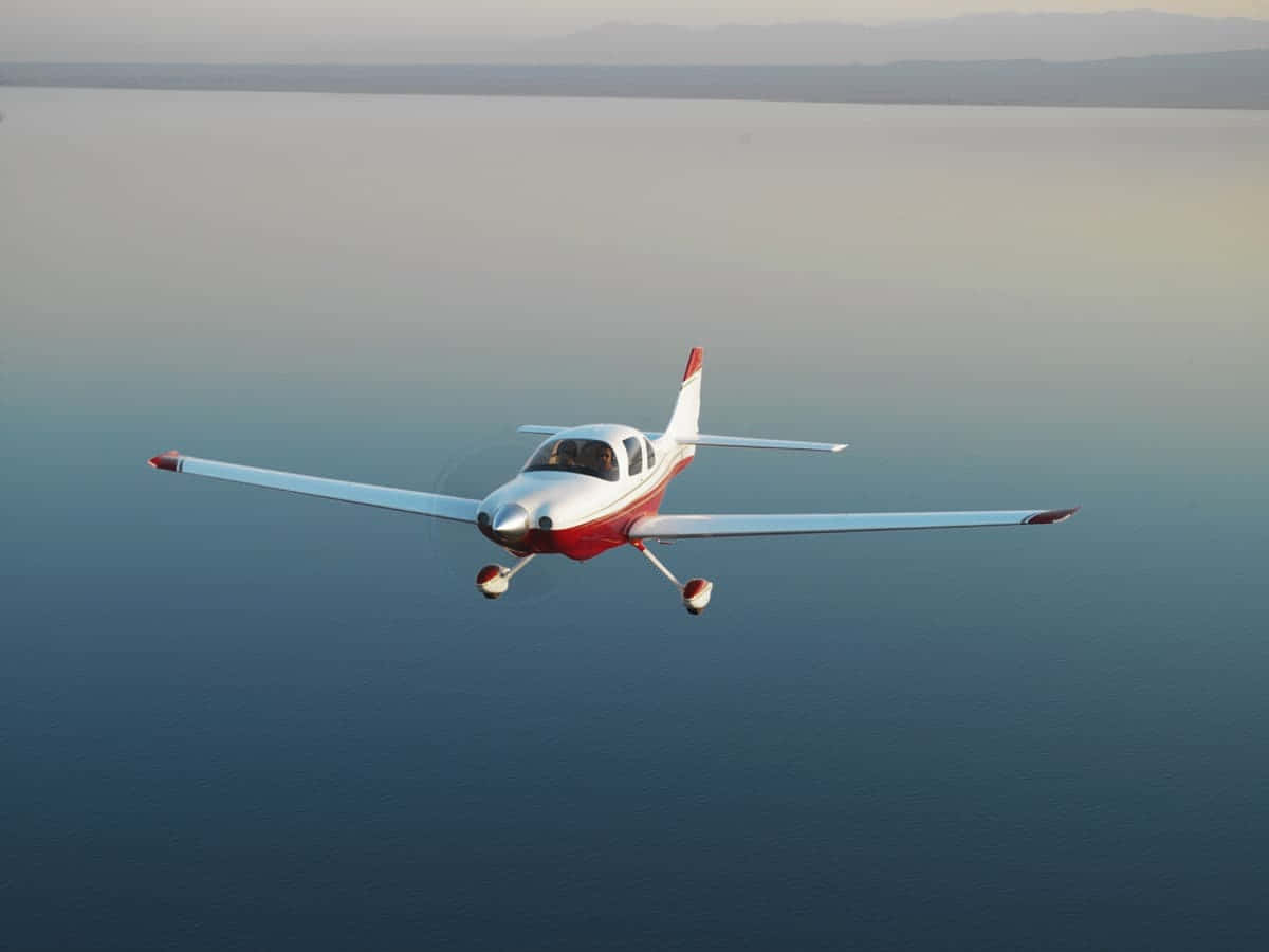 Cesna 400 Small Airplane Gliding Over Water Background