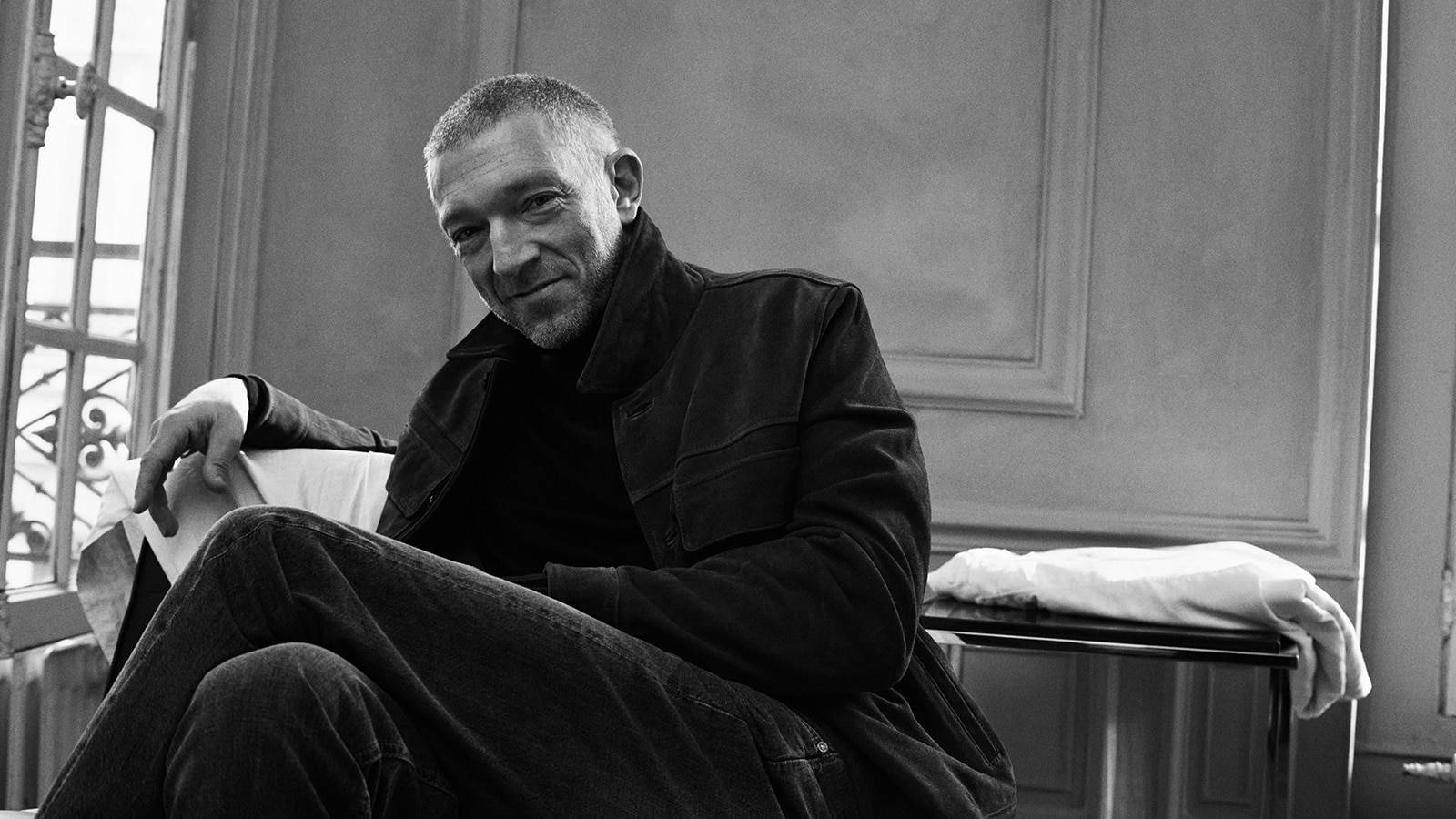 Charismatic Vincent Cassel Seated In Greyscale Photograph Background