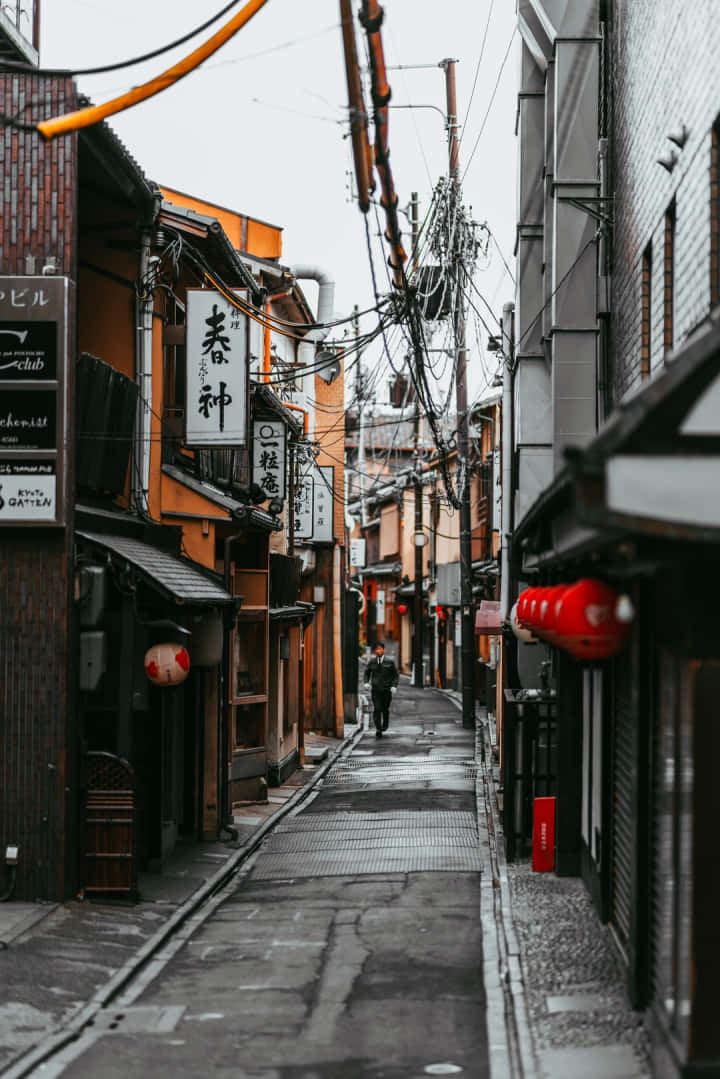 Charming Exploration - A Solitary Wanderer Traverses A Narrow Street In Japan. Background