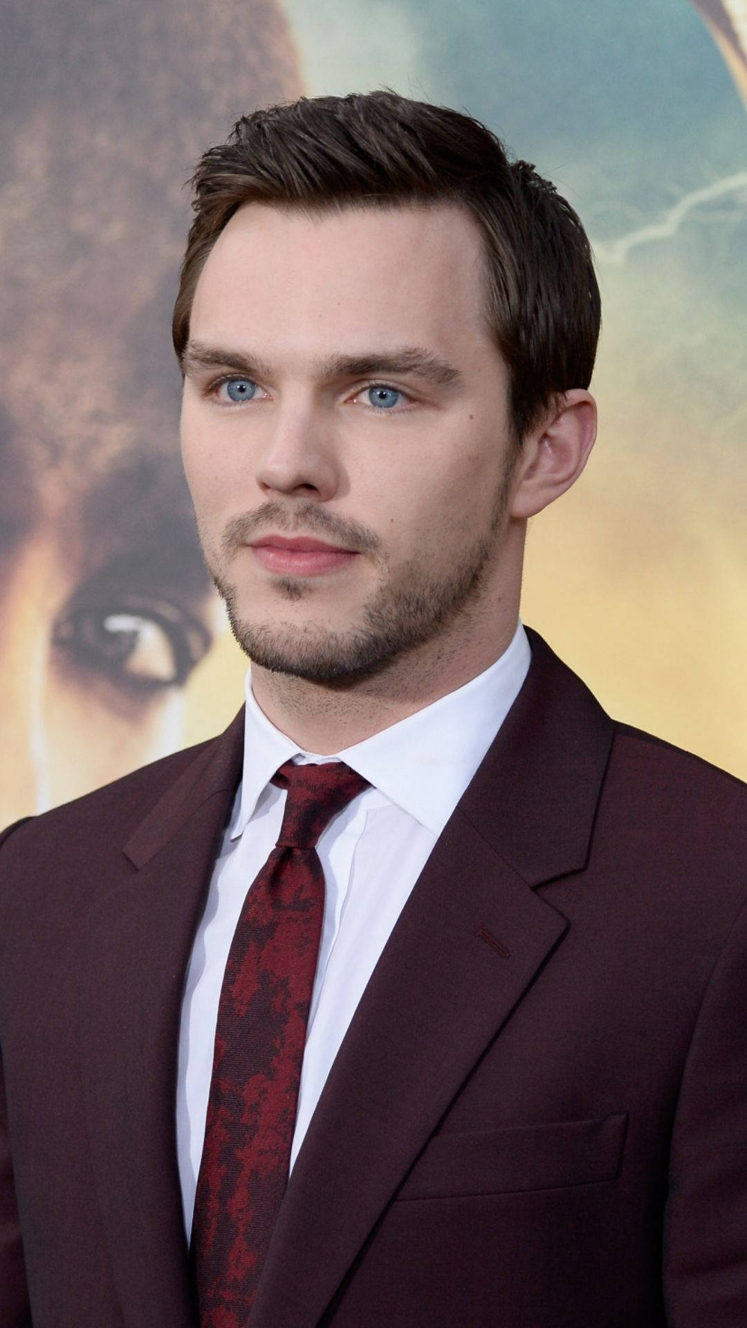 Chic Nicholas Hoult Dressed In A Classy Maroon Suit Background