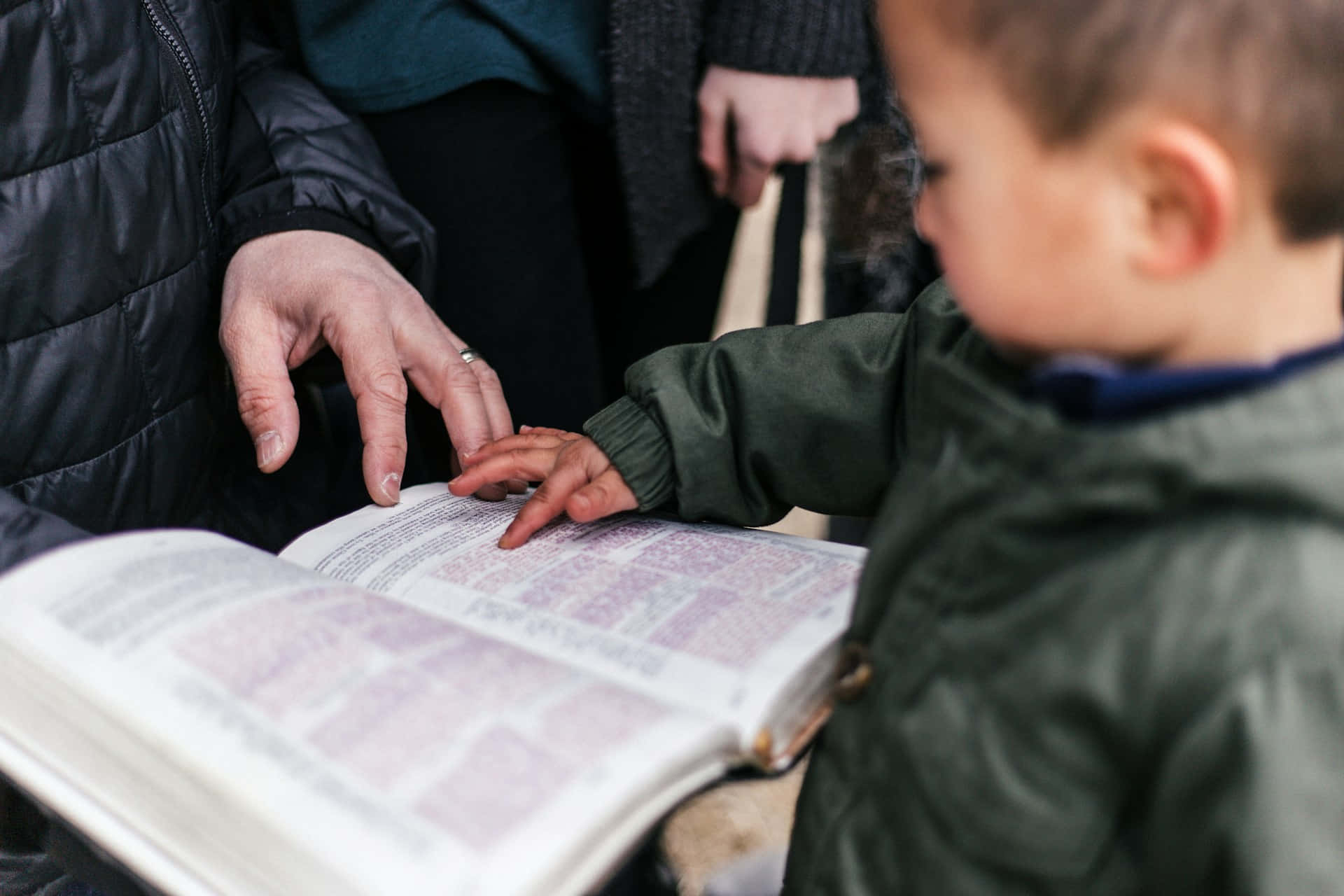 Child Learning From Book With Adult