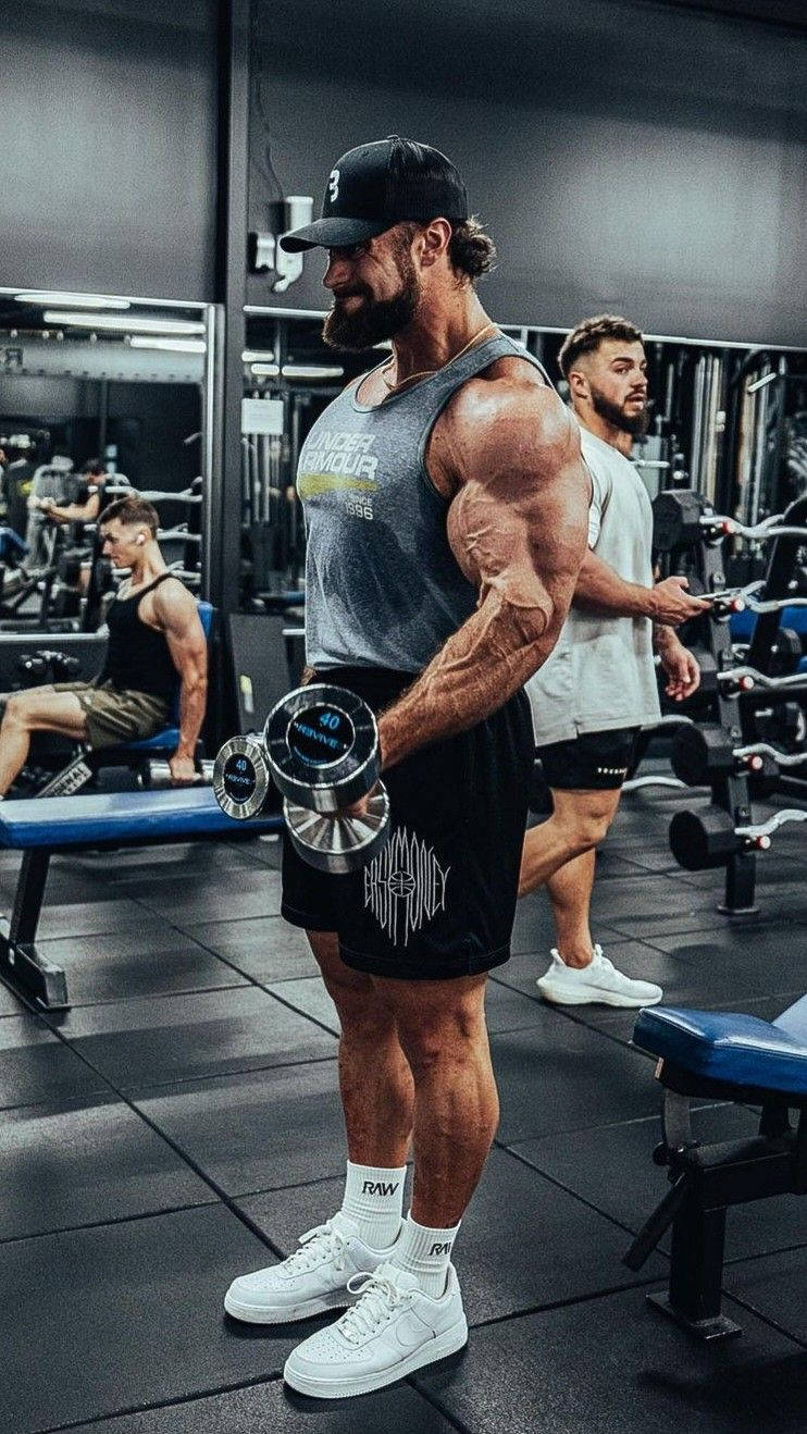 Chris Bumstead Side Profile With Dumbbells Background