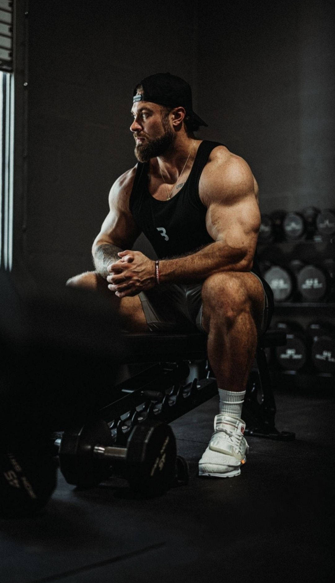 Chris Bumstead Sitting On Weight Bench Background
