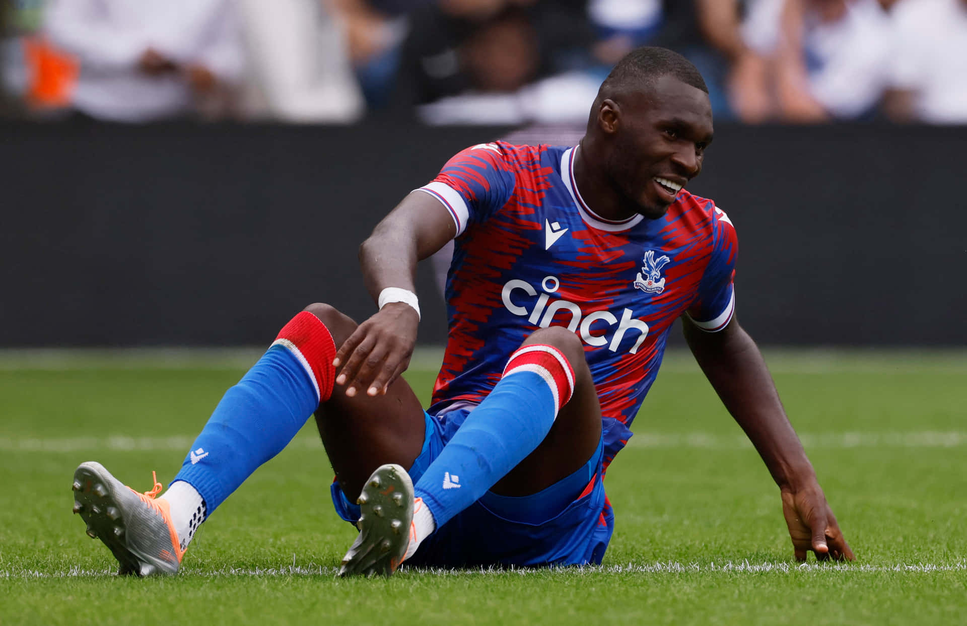 Christian Benteke Sitting On Football Field Background