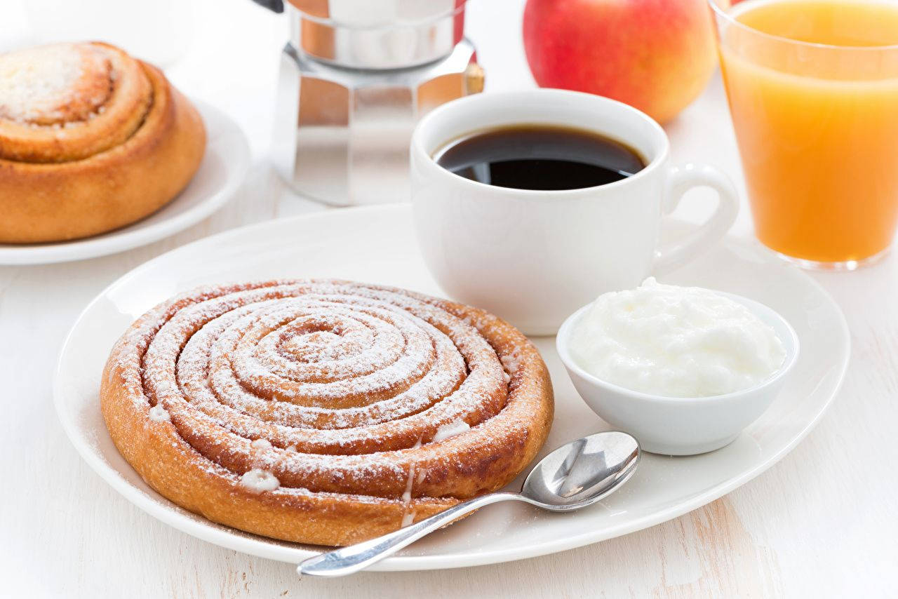 Cinnamon Roll With Confectioner Sugar And Coffee Background