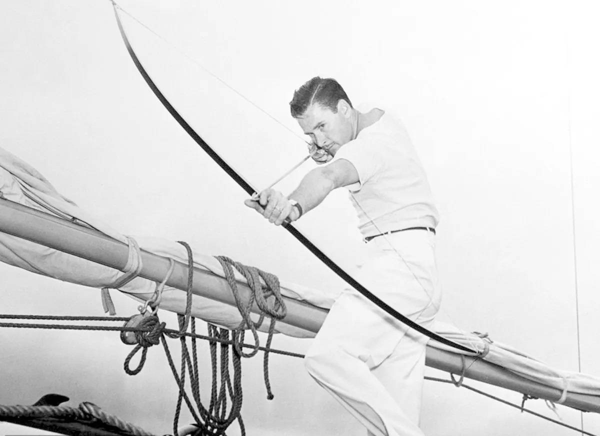 Classic Hollywood Actor, Errol Flynn, In A Dramatic Black And White Shot Aiming A Bow Background