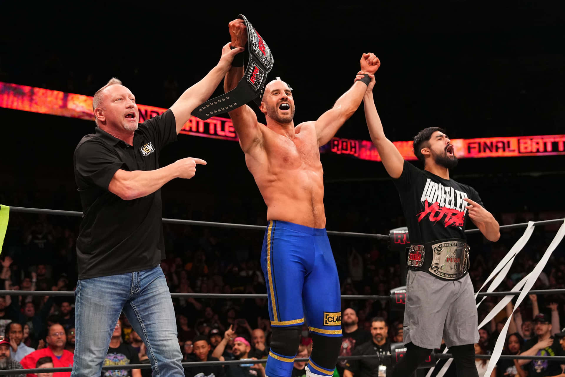 Claudio Castagnoli Hands Raised By Wheeler Yuta Background