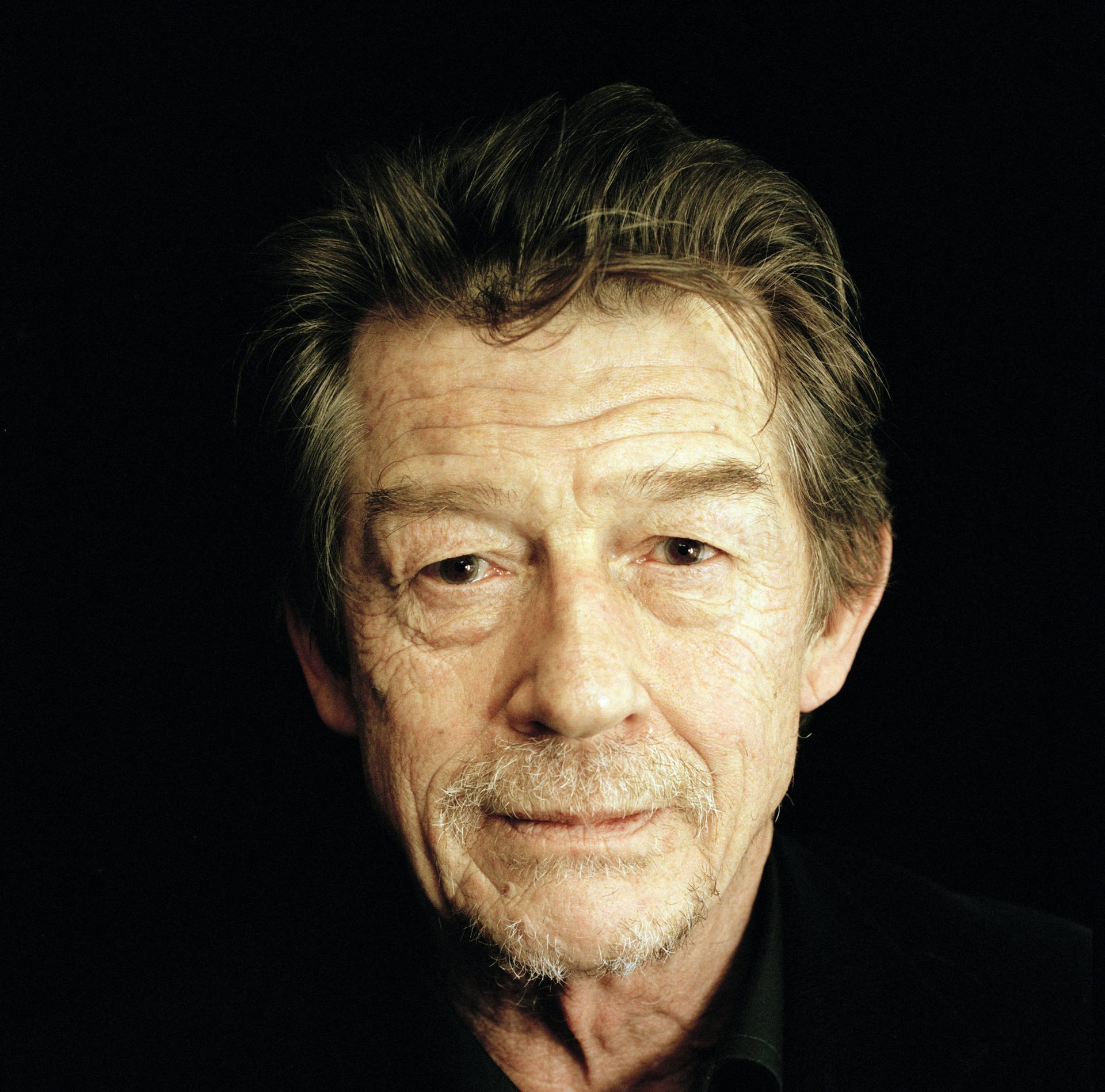 Close-up Portrait Of John Hurt Against A Black Backdrop Background