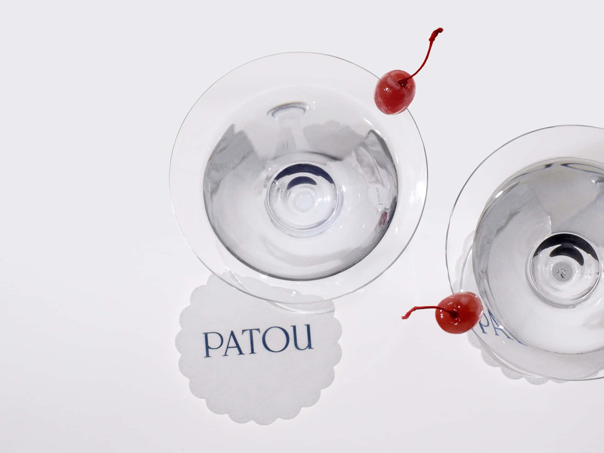 Cocktail Glasses With Patou Logo On Doily Background