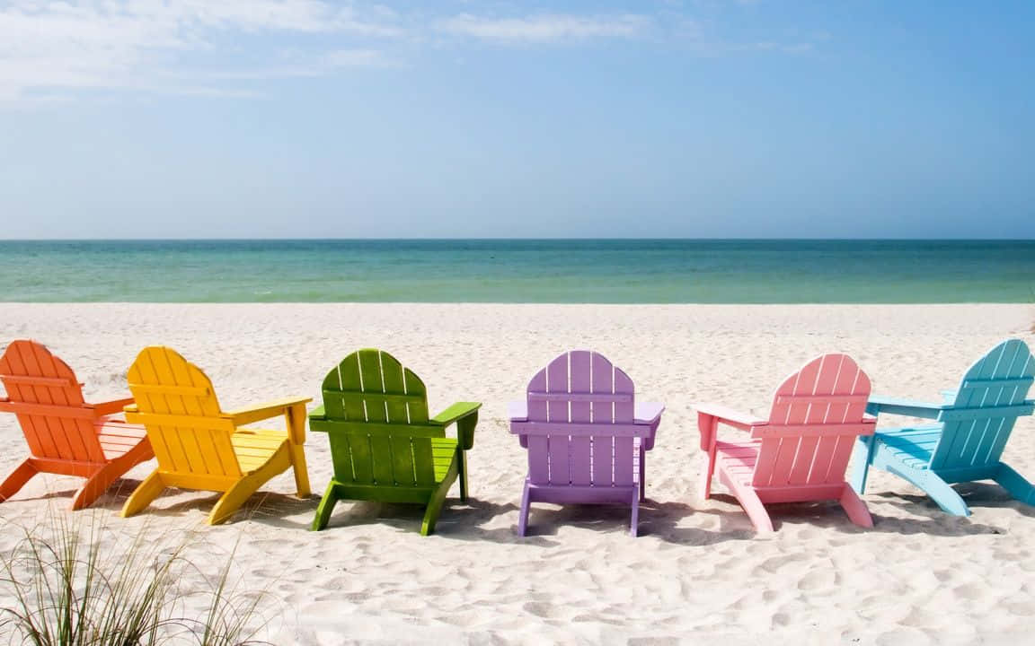 Colorful Adirondack Chairs On The Beach Background