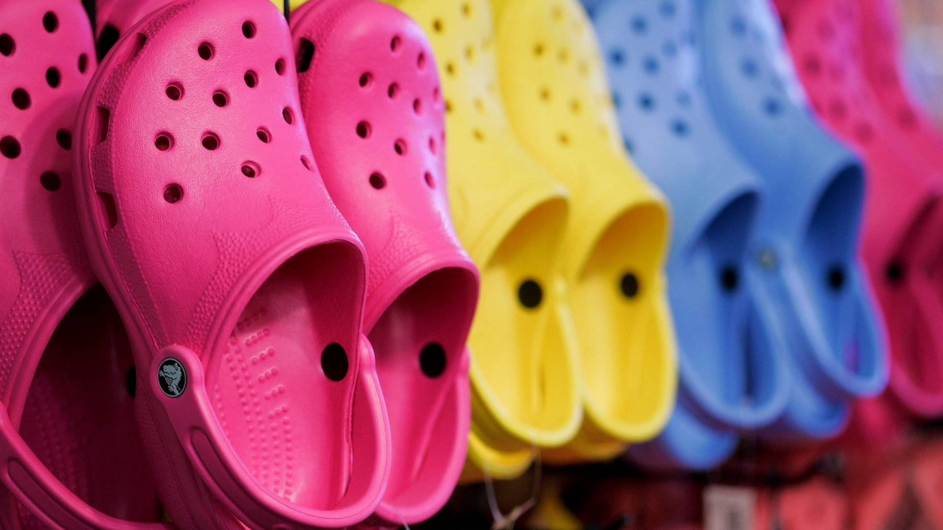 Colorful Array Of Crocs Footwear On Display Background