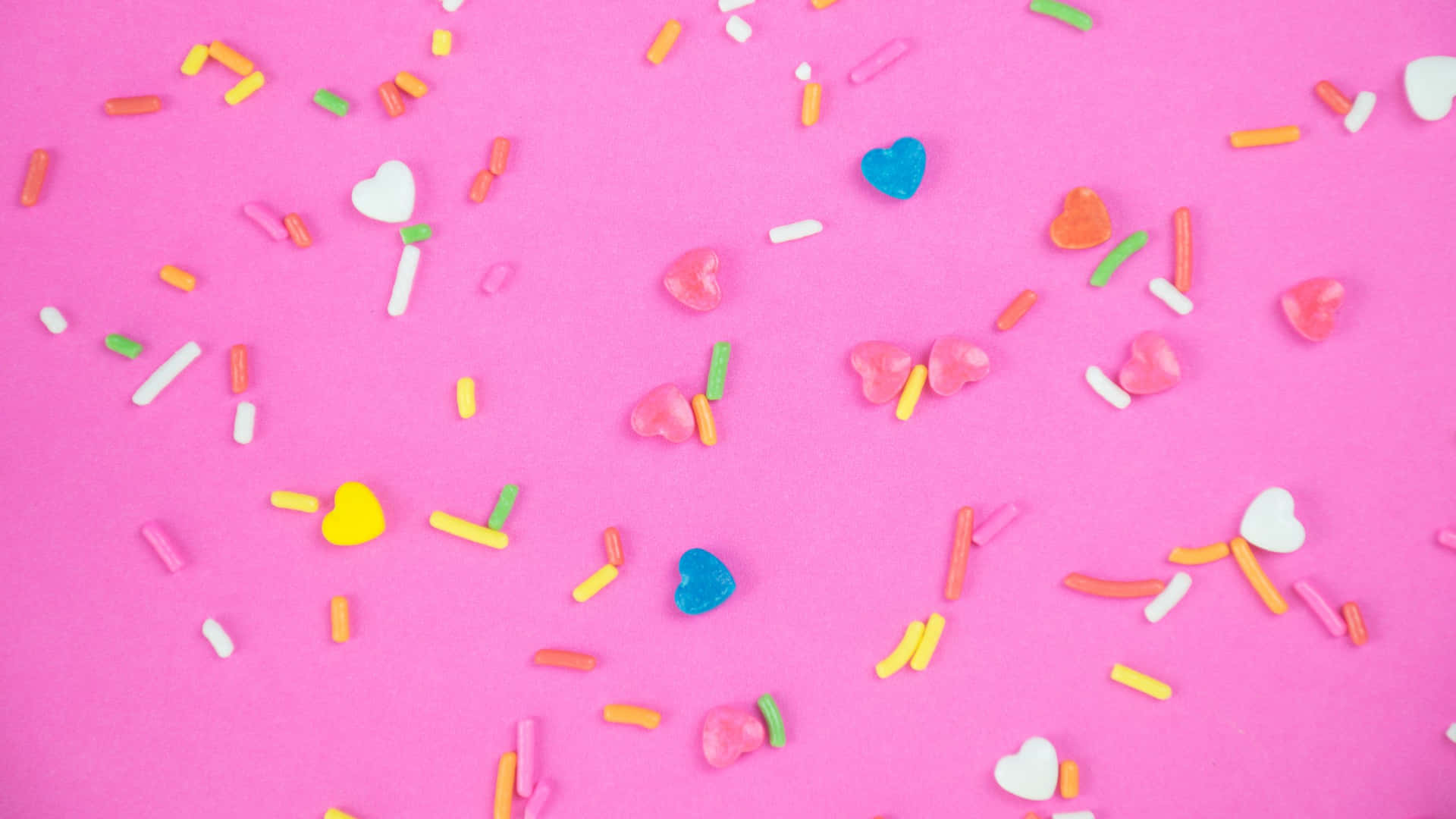Colorful Candy Sprinkleson Pink Background Background