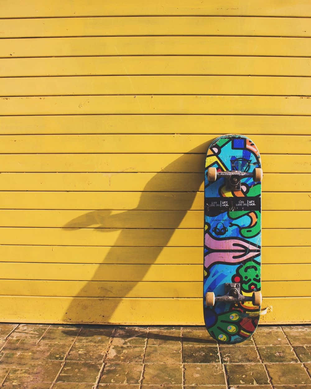 Colorful Skateboard Against Yellow Wall Background