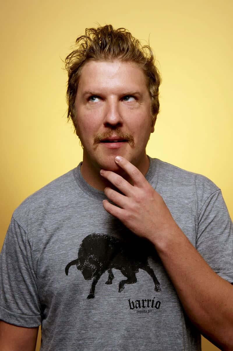 Comedian Nick Swardson, On Stage In Front Of A Microphone Background