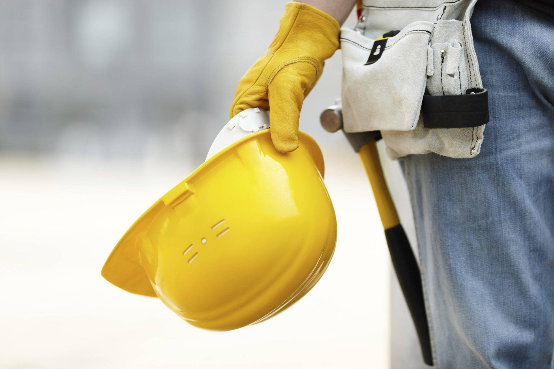 Construction Worker's Hand Holding A Hard Hat