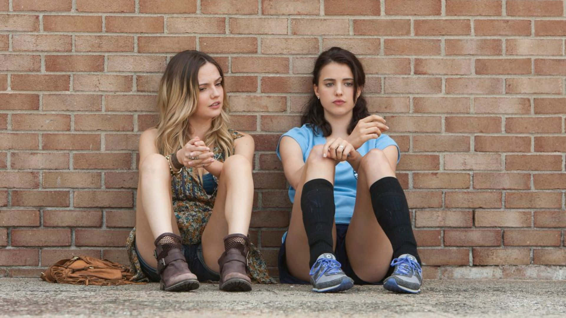 Contemplative Friends Sitting Against Brick Wall Background