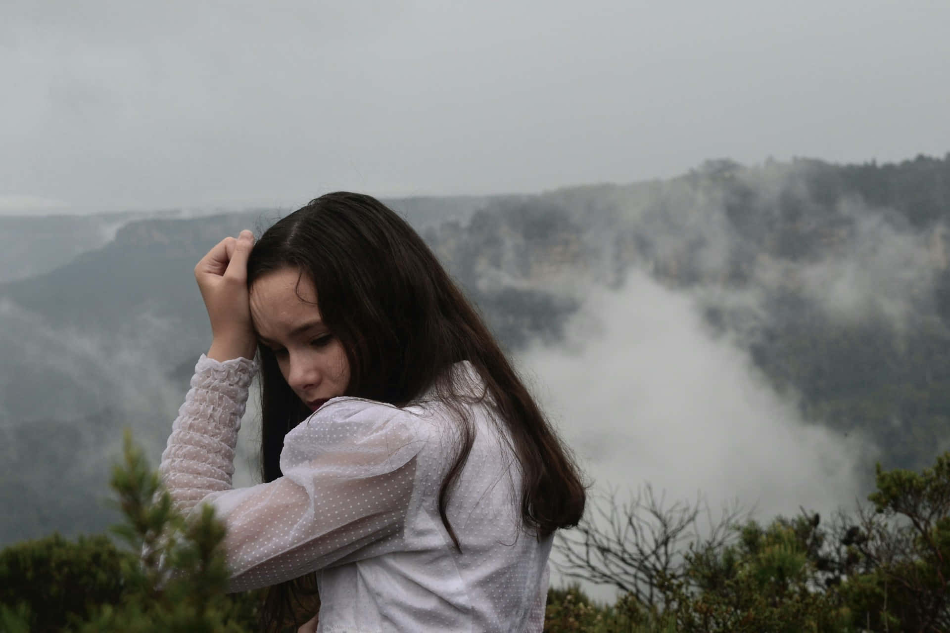 Contemplative Young Girl Misty Mountain Backdrop
