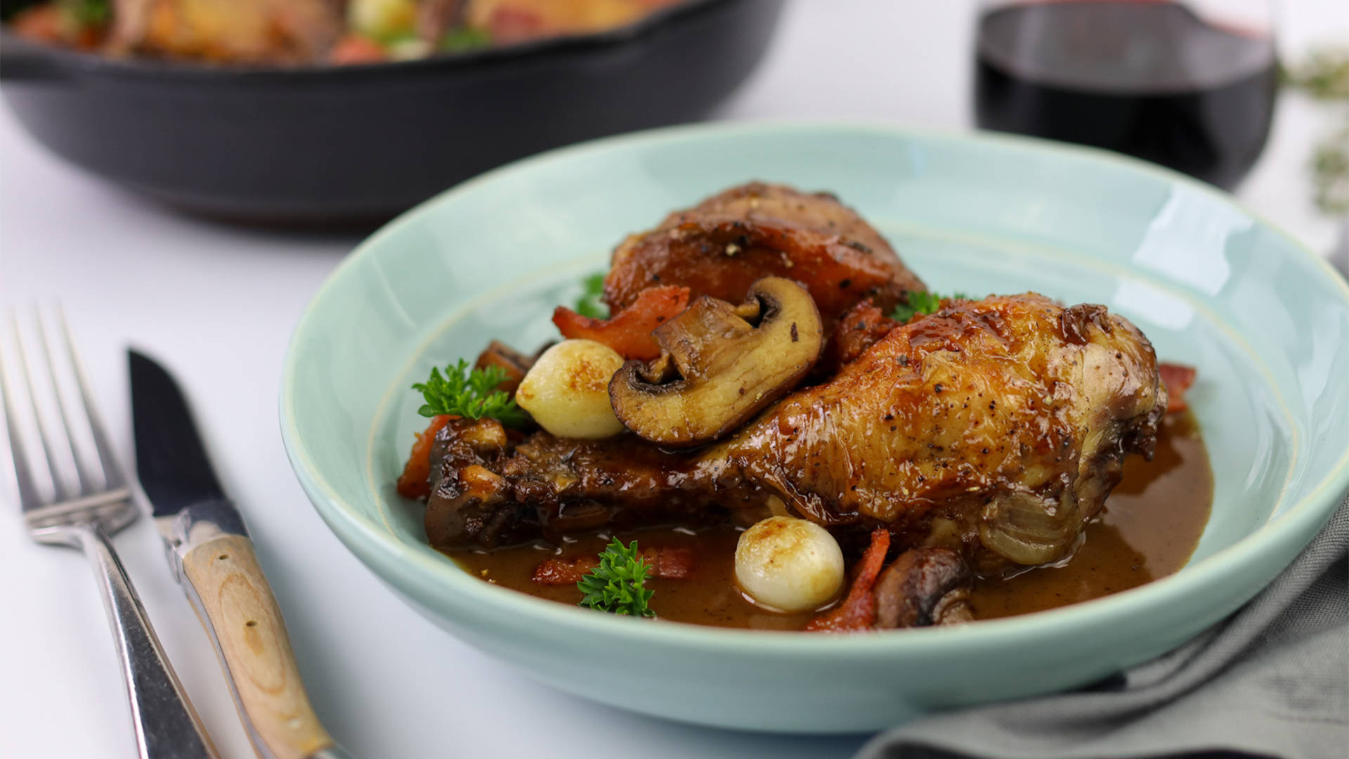 Coq Au Vin On A Ceramic Plate With Cutlery Background