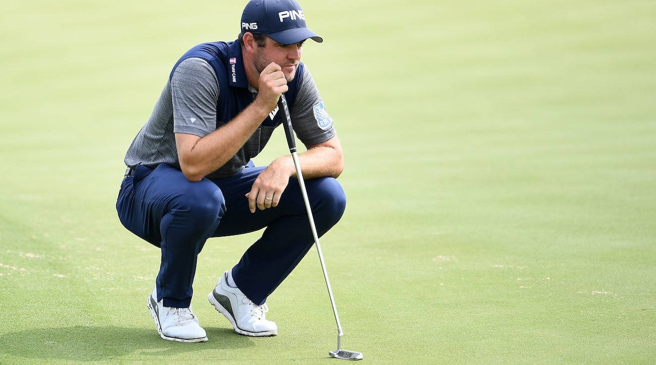 Corey Conners Squatting On A Golf Course Background