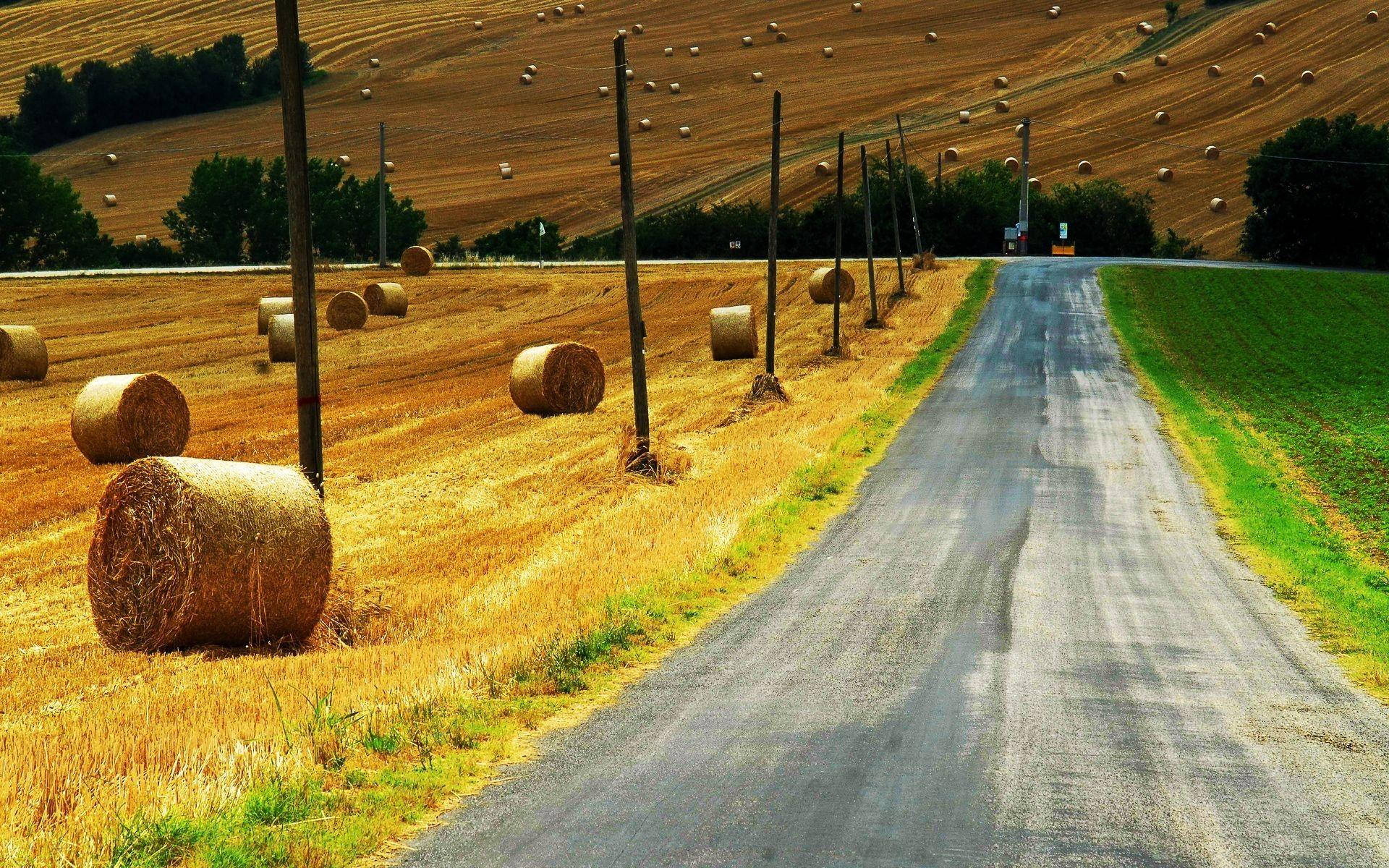 Country Road With Rolled Up Haystack Background