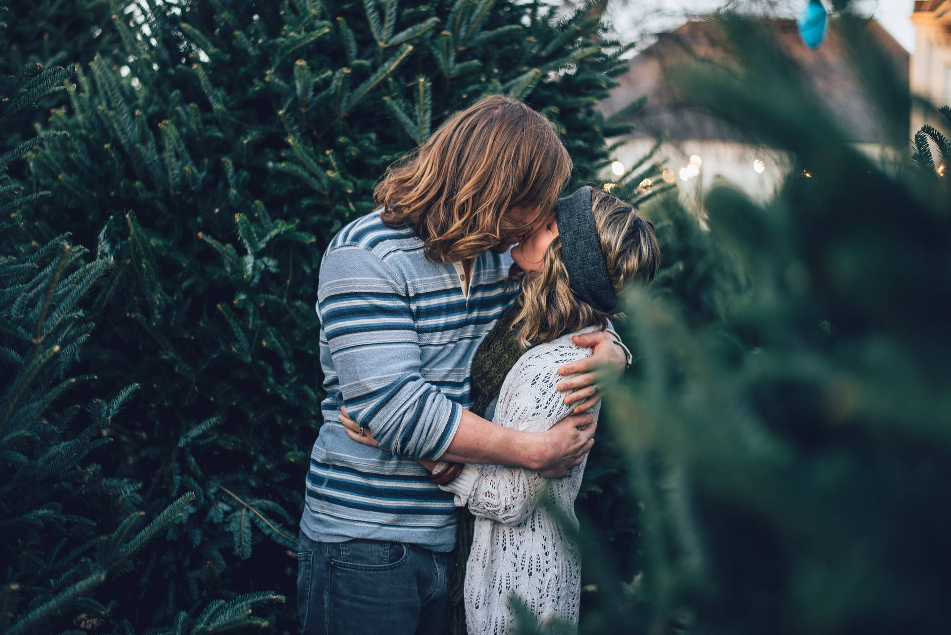 Couple Hugging And Kissing By The Pine Trees Background