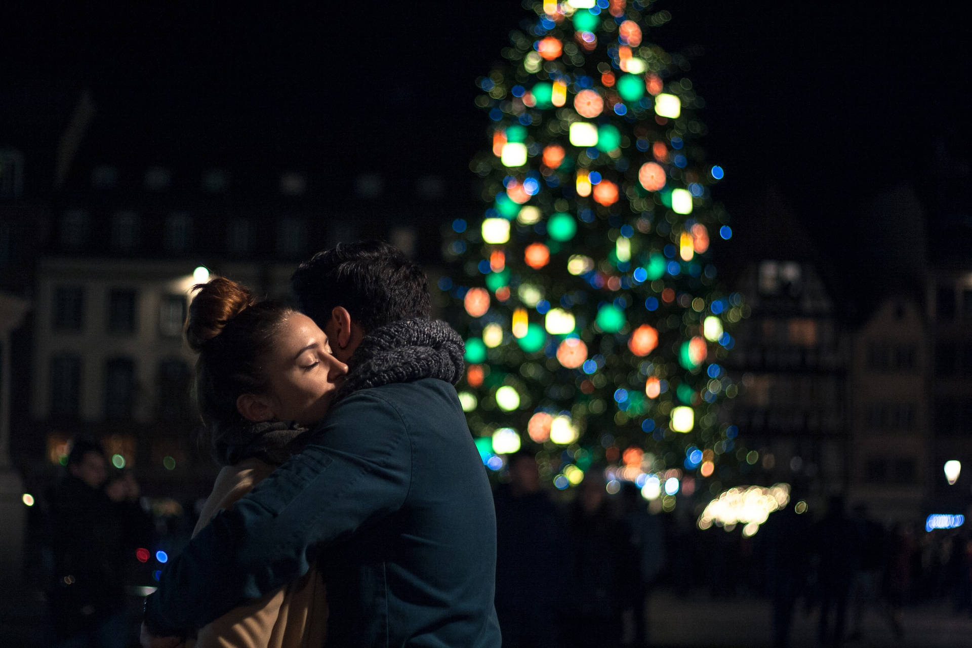 Couple Hugging By A Christmas Tree Background