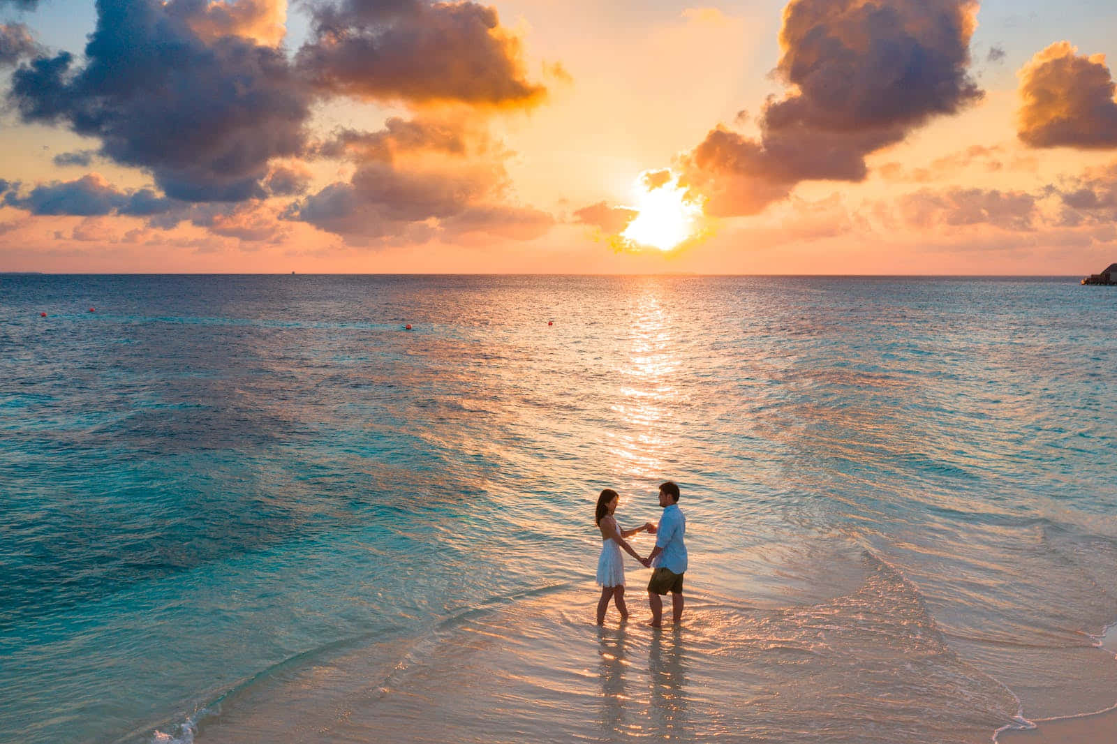 Couple Standing On The Beach At Sunset