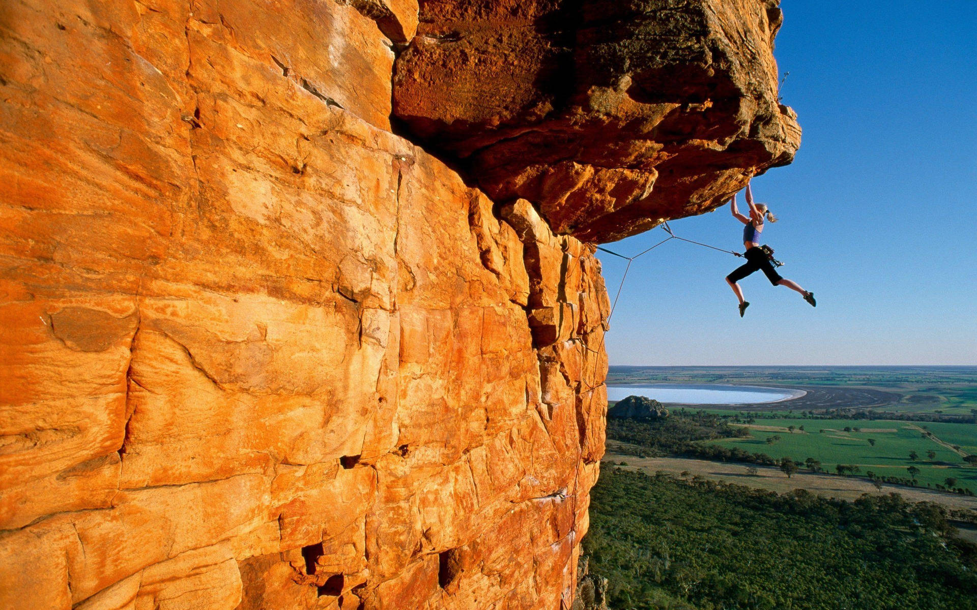 Courageous Woman Mountaineering On Rocky Cliff Background