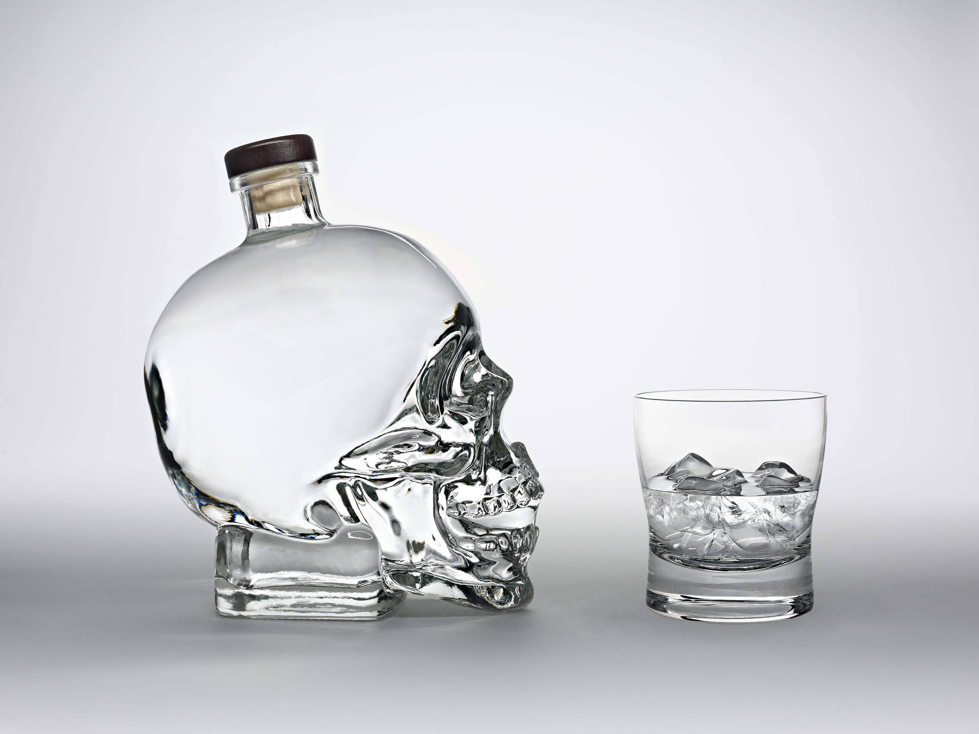 Crystal Head Vodka Bottle Facing A Glass Background