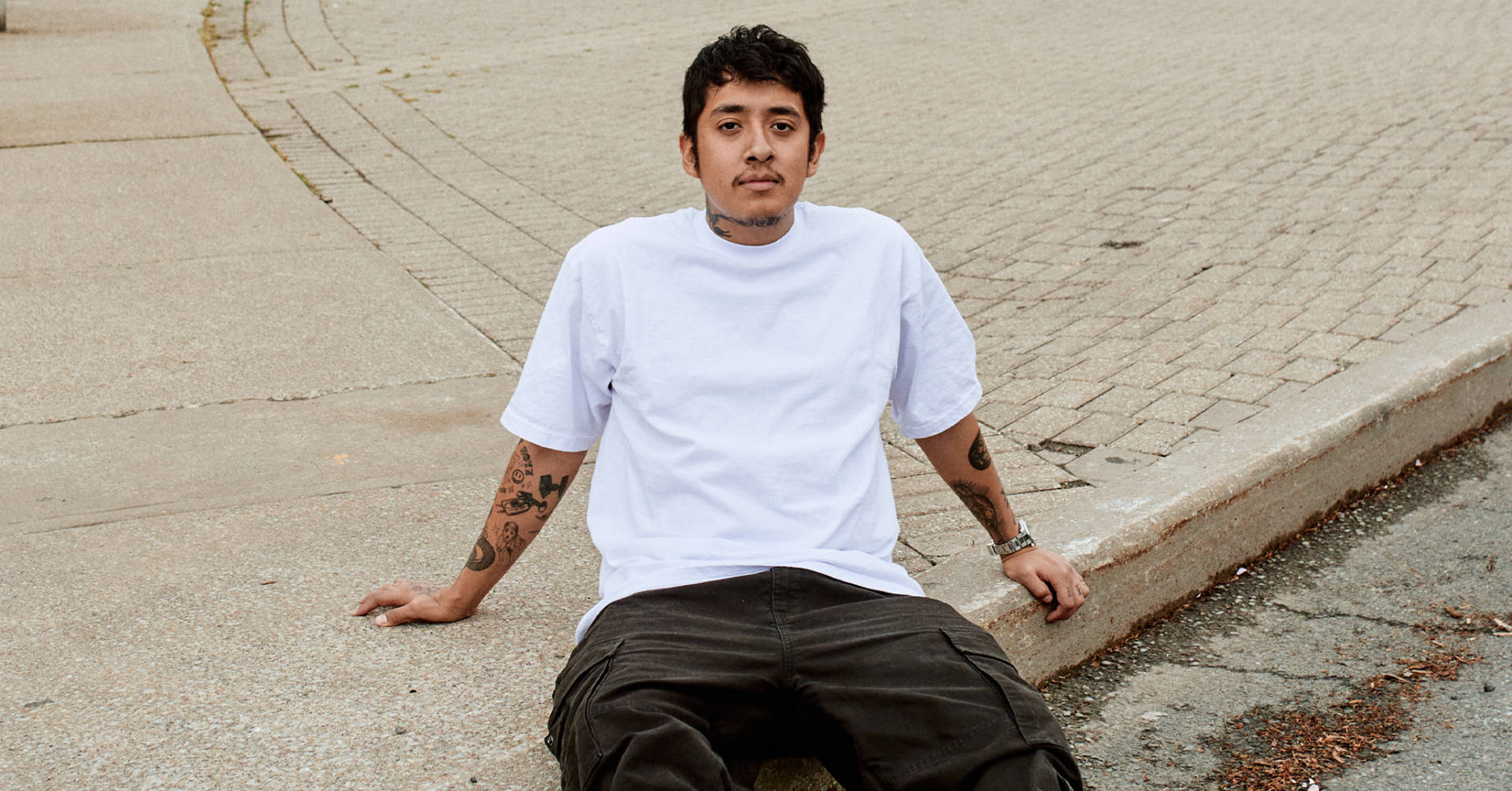 Cuco Sitting Beside The Street Background