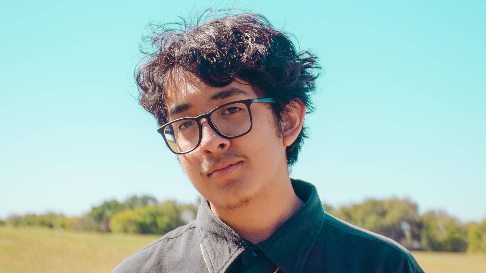 Cuco With His Black Shirt And Eyeglasses Background