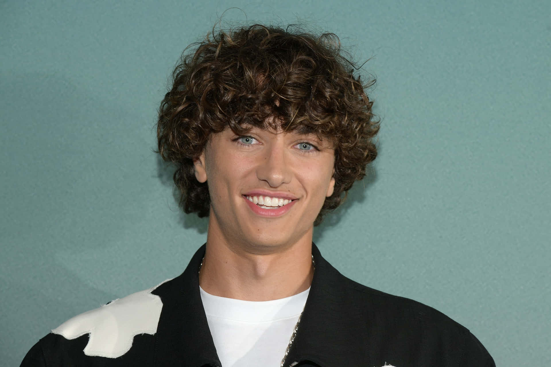 Curly Haired Man Smiling At Event Background